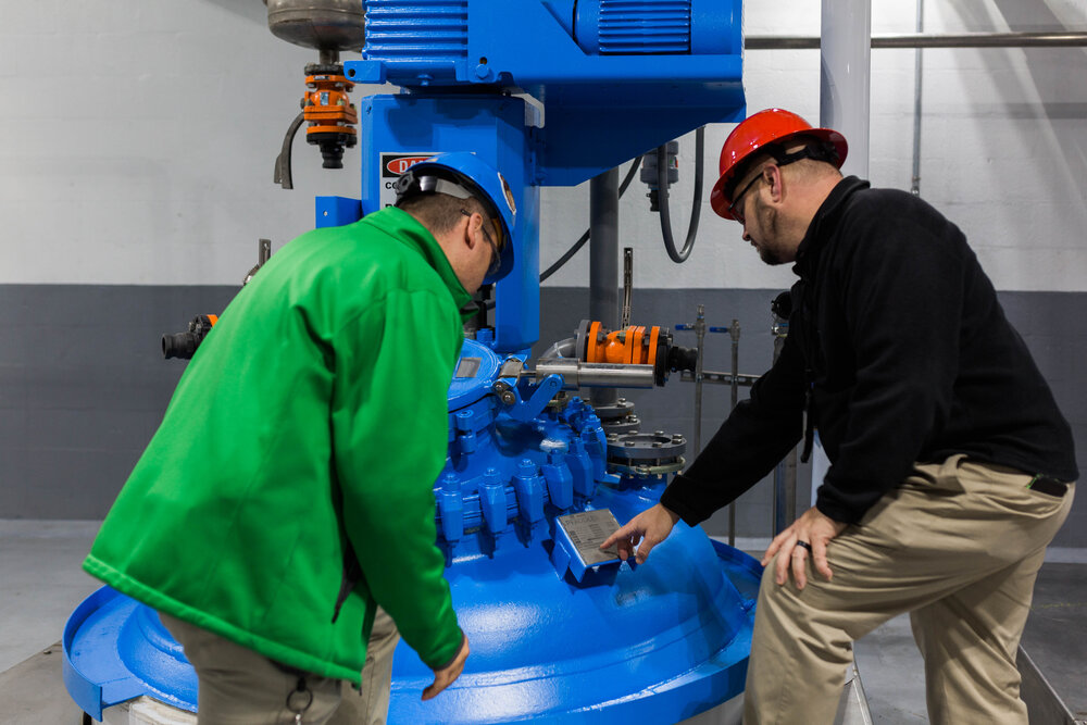two men looking at a blue reactor